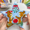 Hands holding a Christmas beaded star ornament featuring a couple of squirrels under a mistletoe with bead tubes in the background