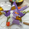 Flat lay of the finished Snowman Peyote Star surrounded by craft supplies and Christmas decor
