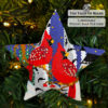 beaded star ornament with a couple of red cardinals perched on branches in front of a church hanging on a Christmas tree
