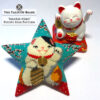 Beaded star ornament featuring a lucky cat with an actual Maneki-Neko figurine in the background