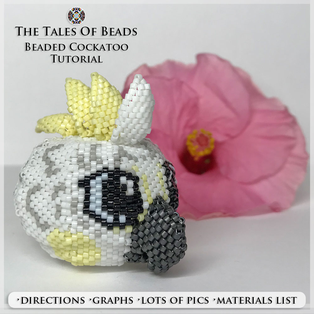 A cute beaded cockatoo made with Miyuki Delica seed beads pictured with a hibiscus flower on white background