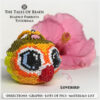A cute beaded lovebird made with Miyuki Delica seed beads pictured with a hibiscus flower on white background