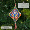 Close-up of the beaded pod ornament with a geometric motif on a white background displayed on a Christmas tree