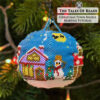A beaded bauble featuring a snowman, a decorated tree, tiny houses with transparent bead windows glowing