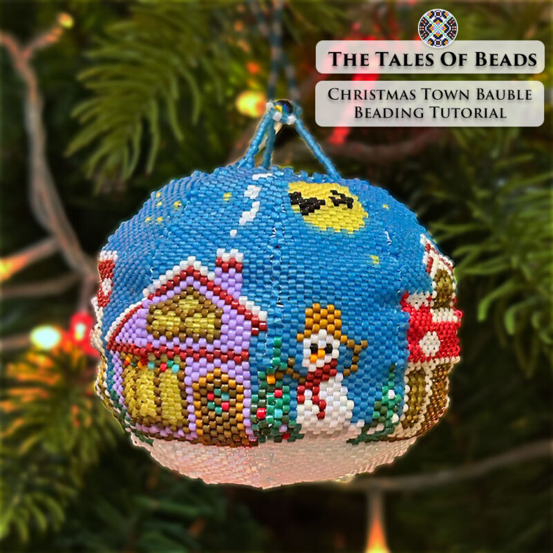 A beaded bauble featuring a snowman, a decorated tree, tiny houses with transparent bead windows glowing