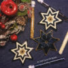 A flat lay of three seven-pointed beaded stars with bead tubes and a Christmas wreath