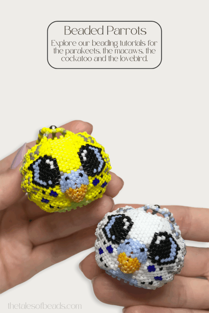Two beaded parakeet heads held in hands on white background