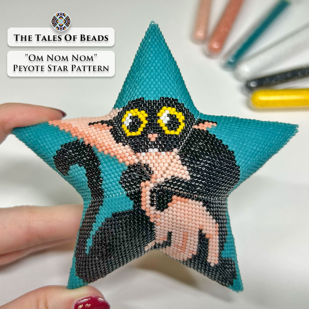 A hand holding a Christmas beaded star ornament featuring a cute black cat