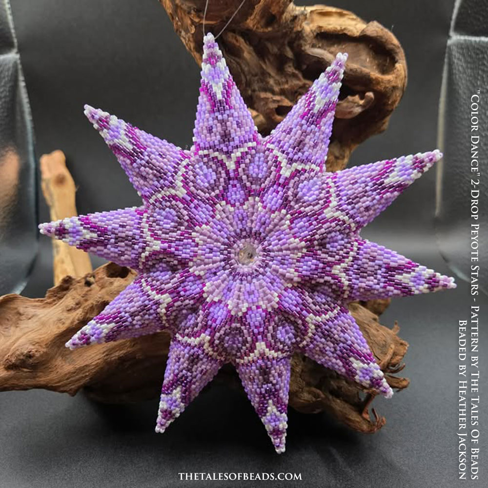 Handcrafted 2-draft peyote star in shades of purple displayed against a natural branch