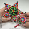 A set of matching peyote stitch ornaments with a vibrant floral pattern held in hands
